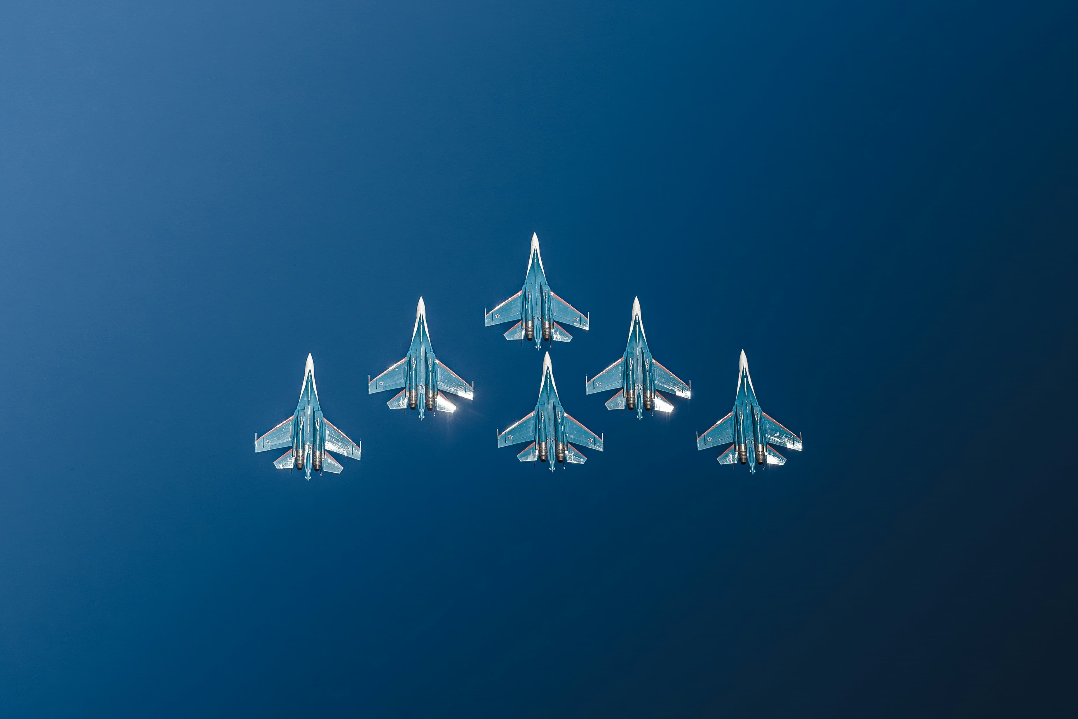 Six fighter jets in tight delta formation against a deep blue sky